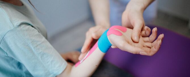 Close-up of a therapist applying kinesio tape for pain relief during a therapy session.